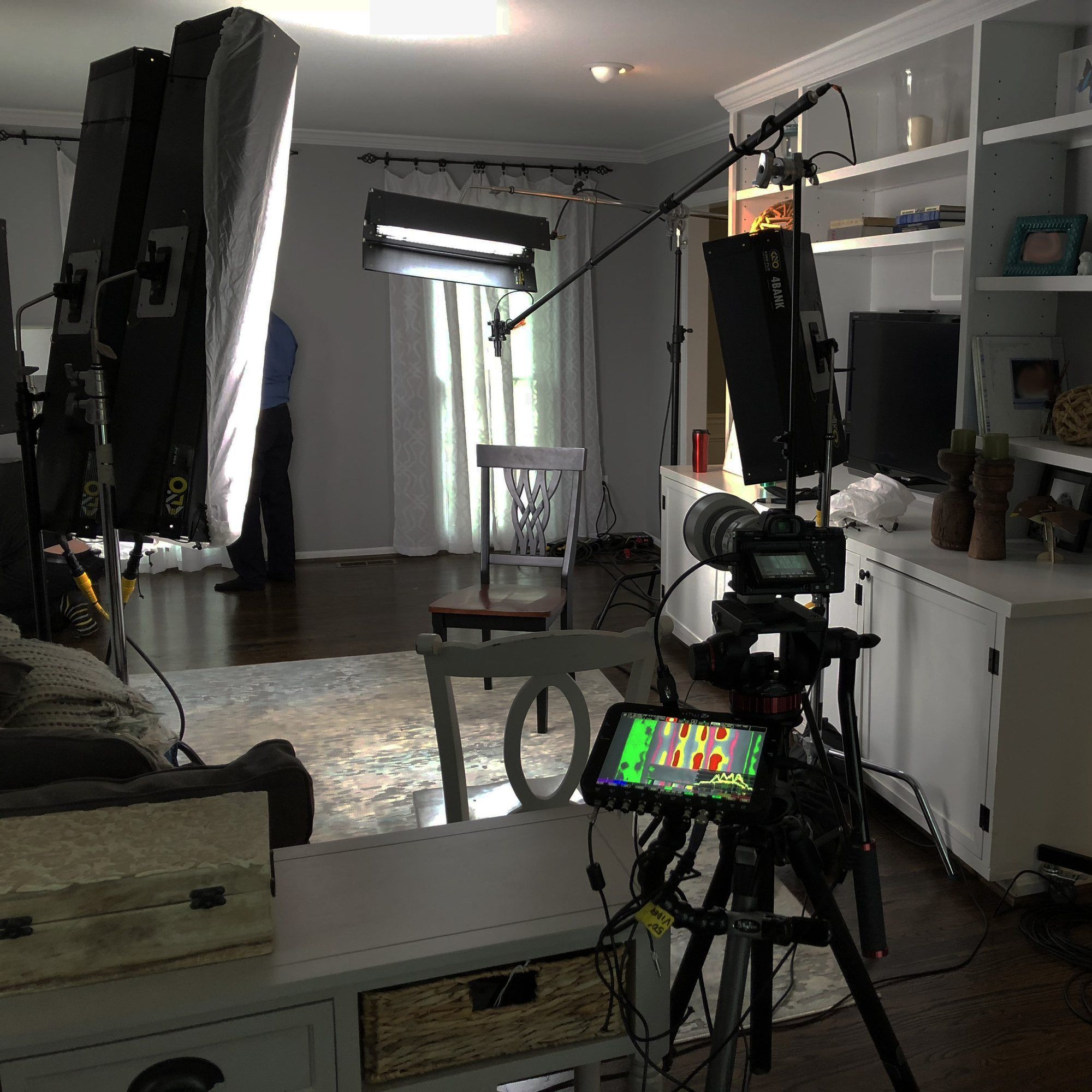 Lights and a camera on a tripod set up for an interview in a living room.